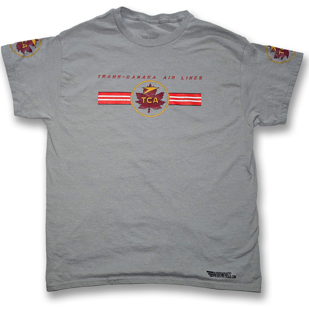 A gray short-sleeve t-shirt featuring a Trans-Canada Air Lines (TCA) graphic on the chest with red and white stripes and a maple leaf logo, plus sleeve patches and a small 'AV8R Wings' mark near the bottom hem.